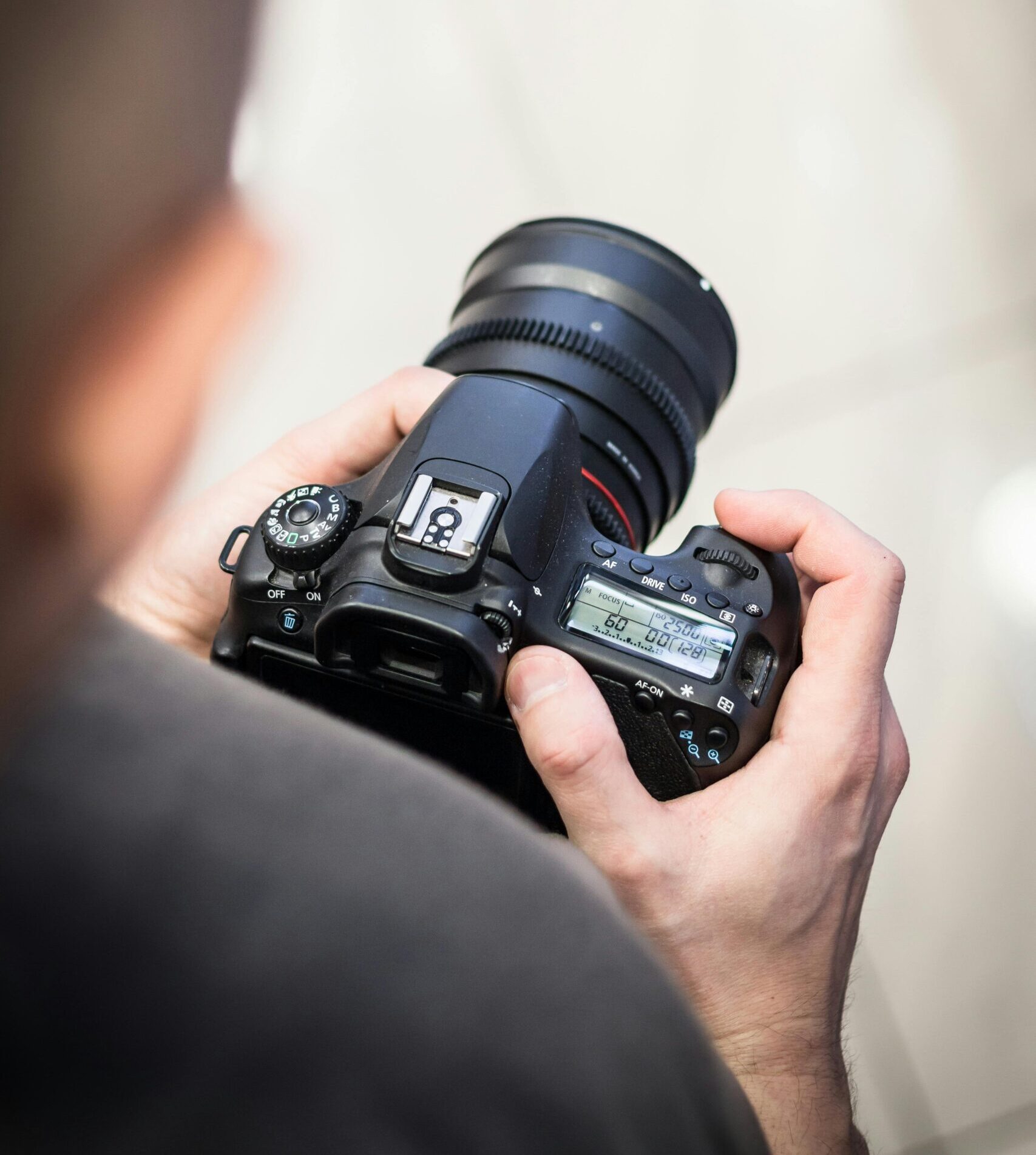 Person adjusting DSLR camera settings indoors for photography.